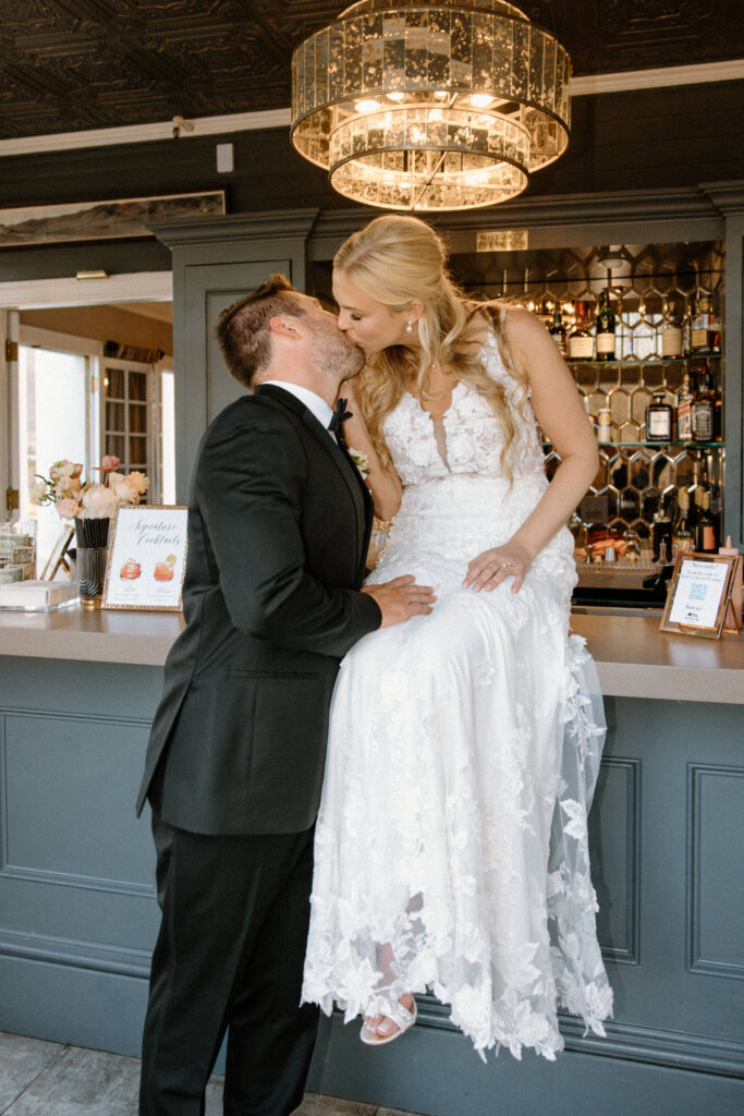 Bride and groom kissing on bar at Manor House